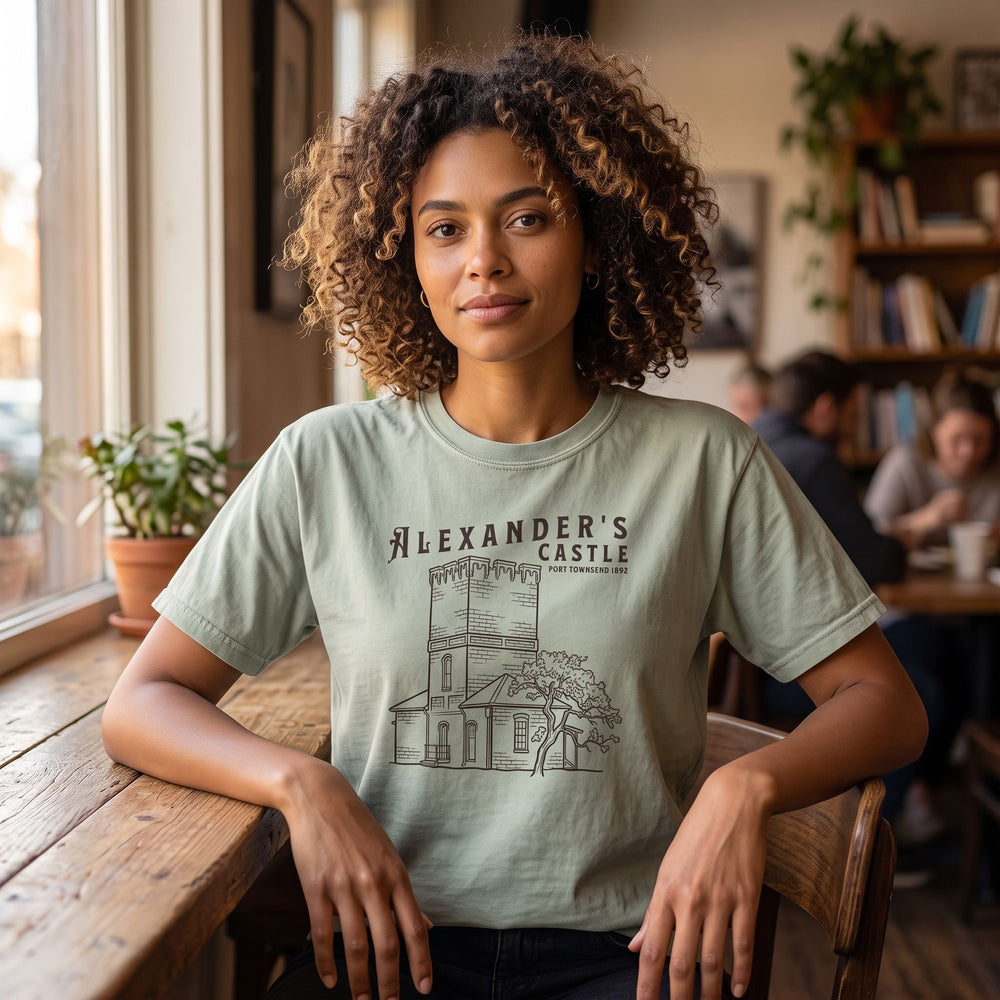 Comfortable wearing of heritage-inspired T-shirt featuring Alexander's Castle in warm, natural indoor scene.