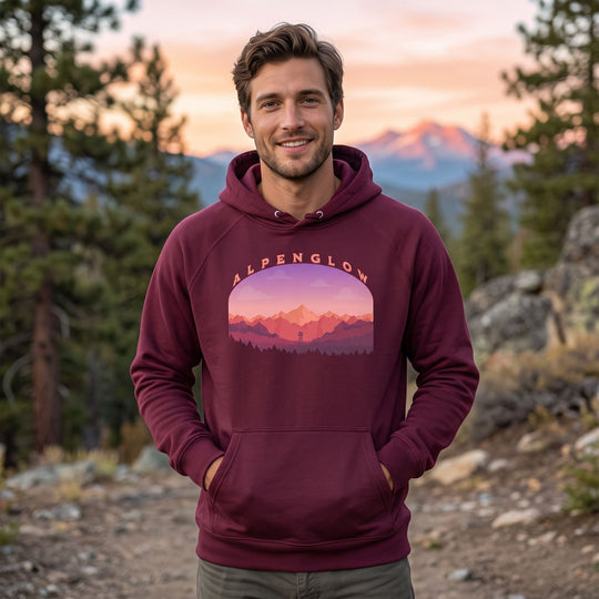 Unisex Alpenglow Summit Raglan Hoodie worn outdoors with greenery and natural daylight, highlighting the colorful mountain and forest design.