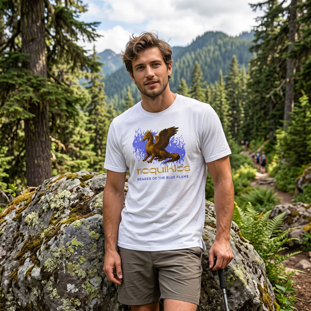 Adult male model wearing The Blue Flame Under Armour Athletic Tee in a natural outdoor setting with greenery, rocks, and water, showcasing active lifestyle.