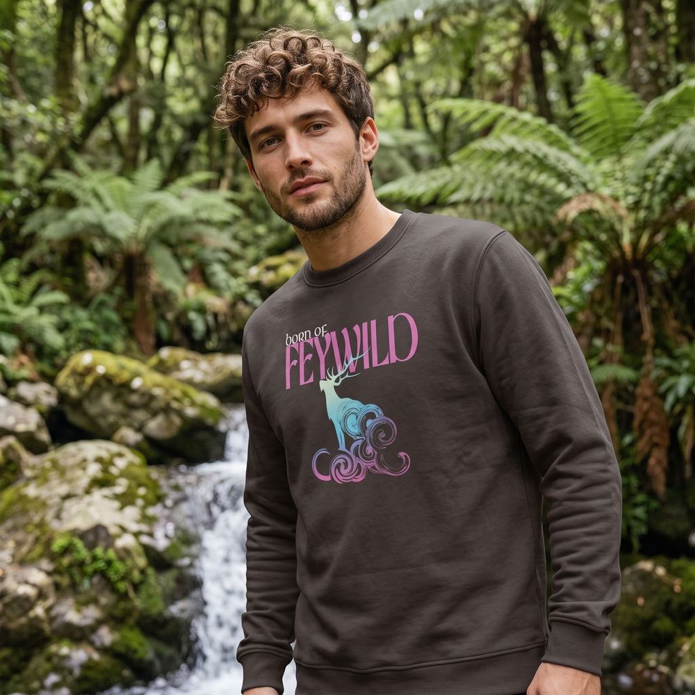 Outdoor scene with a model wearing the Born of Feywild organic sweatshirt featuring a neon-pastel elk stag design, surrounded by greenery under natural daylight.
