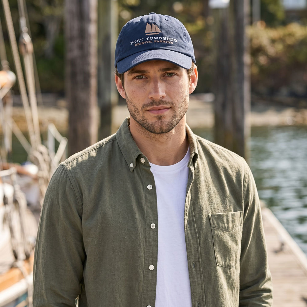 Casual outdoor scene featuring a model wearing the Bristol Fashion Organic Cap against a blurred natural background with greenery.