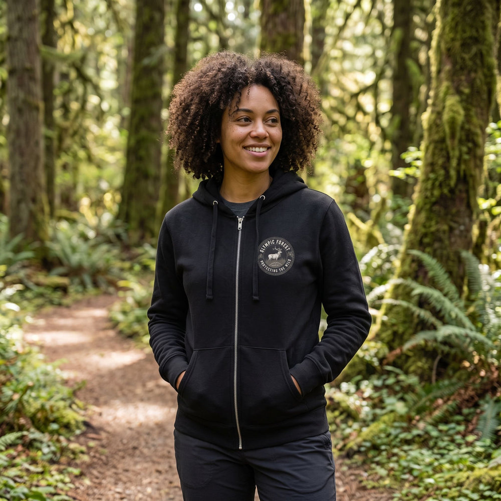 Casual outdoor scene with model in The Olympic Forest Zip Hoodie among natural elements like trees and rocks.