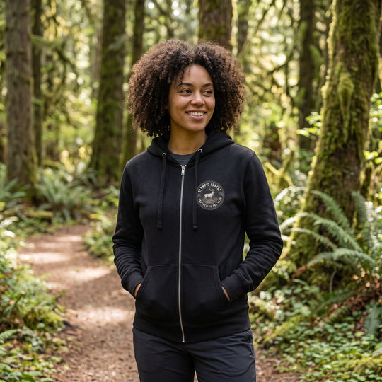 Casual outdoor scene with model in The Olympic Forest Zip Hoodie among natural elements like trees and rocks.