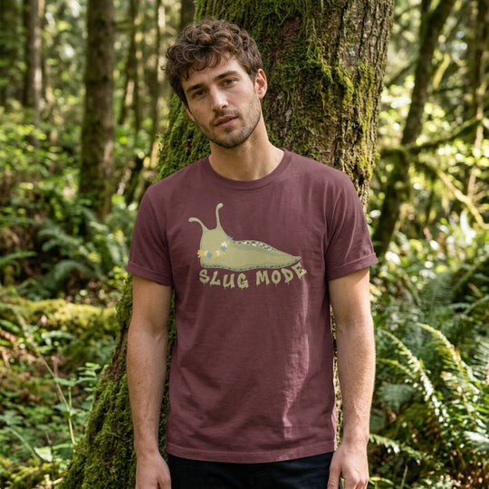 Adult model in relaxed streetwear fit wearing the Slug Mode Heavyweight Tee, posed outdoors with natural sunlight and foliage background.