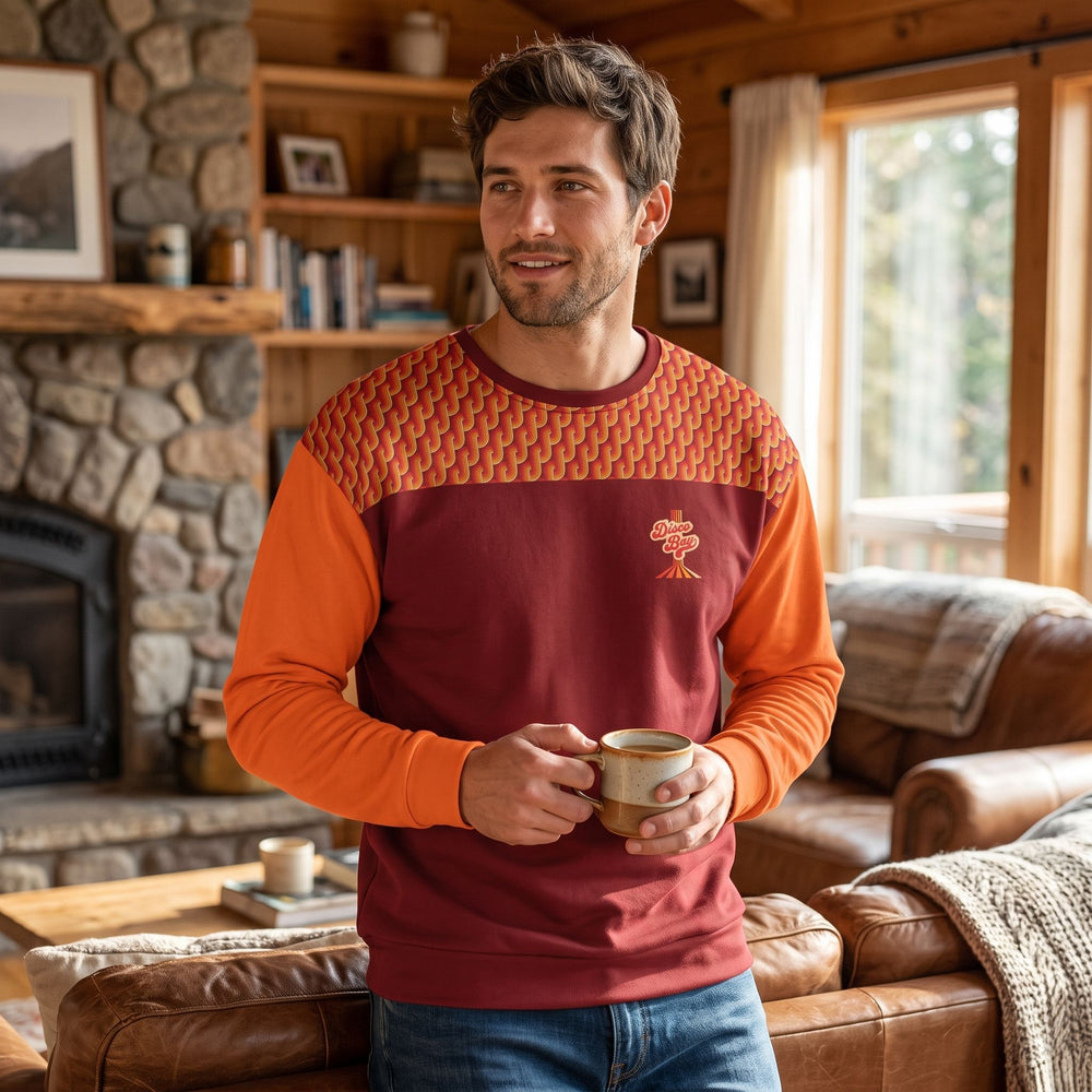 Casual man wearing Disco Bay recycled sweatshirt in a cozy living room setting with warm natural lighting.