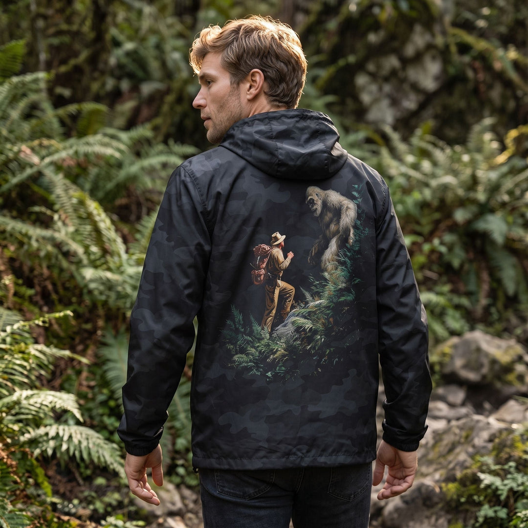 Model Ben wearing the Wild Thing Windbreaker in a natural outdoor environment with rocks and water, emphasizing its lightweight, waterproof features.