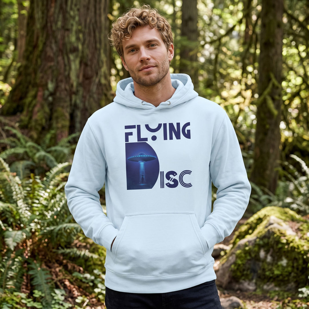 Outdoor scene with a model wearing a UFO abduction hoodie, surrounded by greenery and natural sunlight.