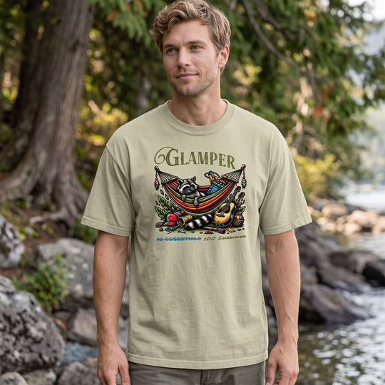 Casual model wearing oversized faded cotton raccoon hammock t-shirt in outdoor nature setting with greenery and bright sunlight.