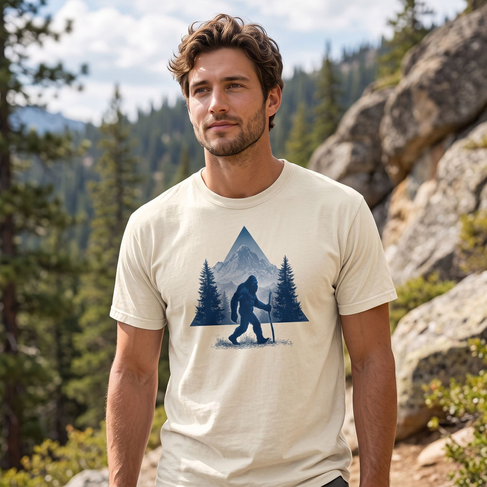 Adult model wearing the High Country Wanderer Garment-Dyed Tee outdoors with greenery, showcasing its vintage look and rugged style.