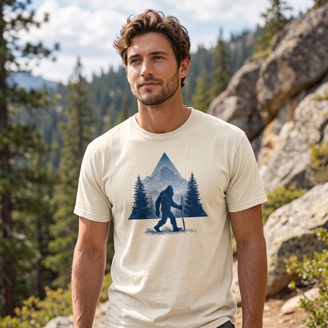 Adult model wearing the High Country Wanderer Garment-Dyed Tee outdoors with greenery, showcasing its vintage look and rugged style.