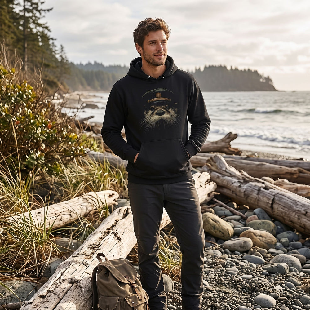 Adult model wearing The Kelp-Bed Boatswain hoodie outdoors with greenery and water, capturing a natural, casual lifestyle setting.