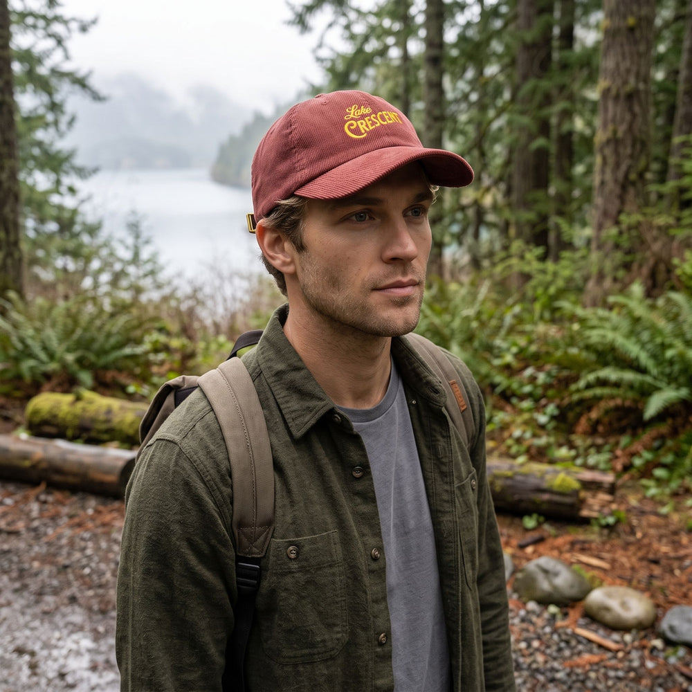 Vintage corduroy cap in outdoor natural setting with greenery and water, worn by model with casual style for adventure look.