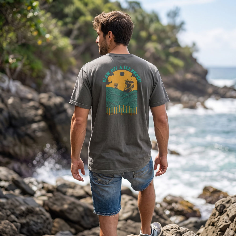 Relaxed-fit heavyweight t-shirt with maritime graphic, worn by a male model in a natural outdoor environment with lush foliage and water.