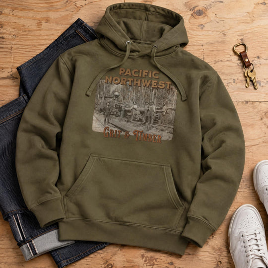 Minimalist flat lay of a cotton-blend pullover hoodie on a plywood backdrop with denim and sneakers.