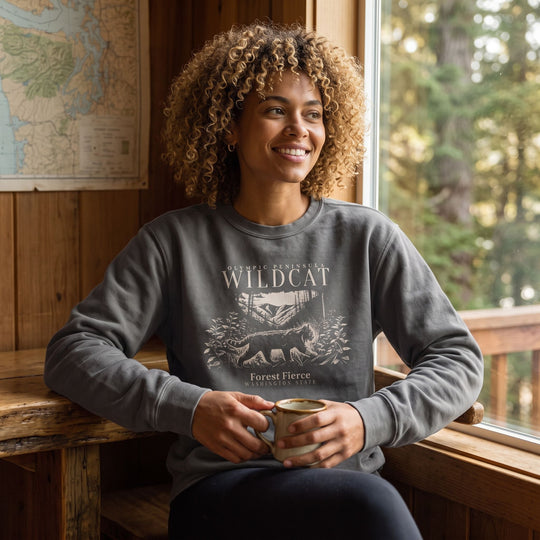Adult with natural curls in Forest Fierce fleece crewneck in a cozy, inviting home environment.