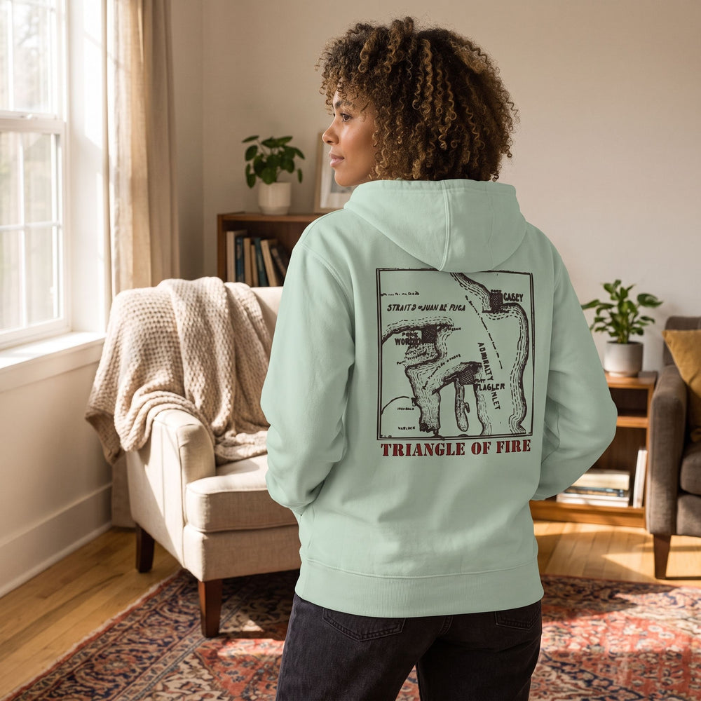 Adult in relaxed fit zip hoodie displaying vintage military map design, in a natural home setting.