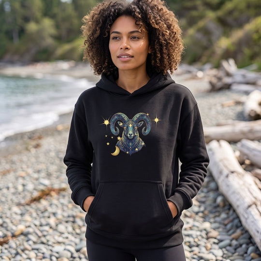 Model wearing Capricorn Mountain Goat organic fleece hoodie outdoors with greenery, bright sunlight, and blurred nature background.