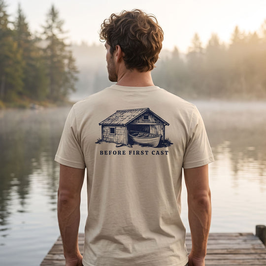 Model wearing First Cast Organic Tee outdoors with blurred foliage and water in the background, emphasizing natural, organic style