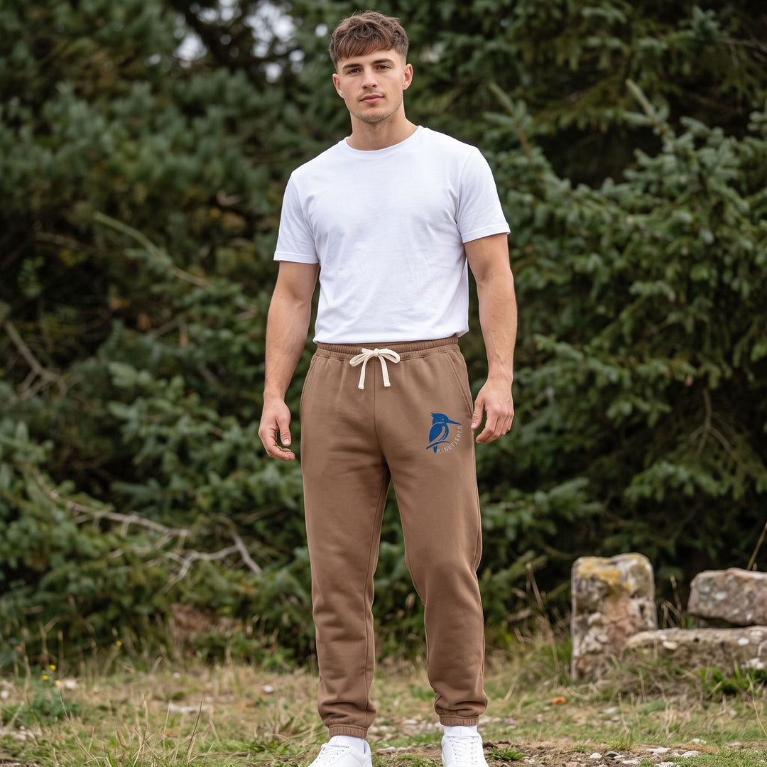 Close up of kingfisher graphic on navy cotton fleece sweatpants worn by a man in a blurred forest environment.