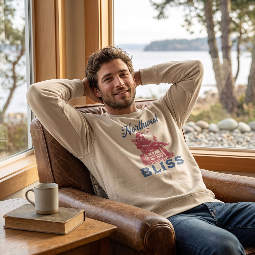 Casual man wearing Northwest Bliss Sweatshirt in a cozy living room with warm natural lighting, relaxing and enjoying a peaceful moment.