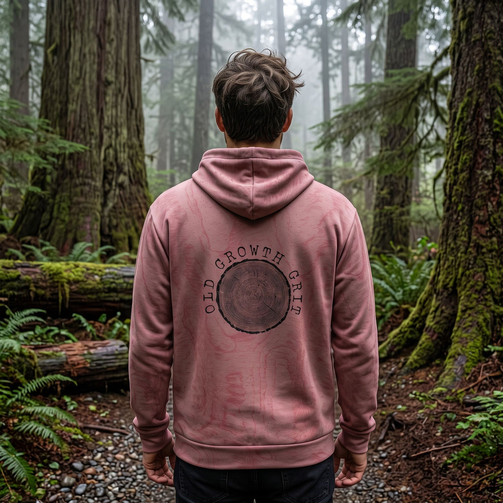 Casual man model wearing Old Growth Grit Hoodie outdoors in natural daylight with blurred foliage background.