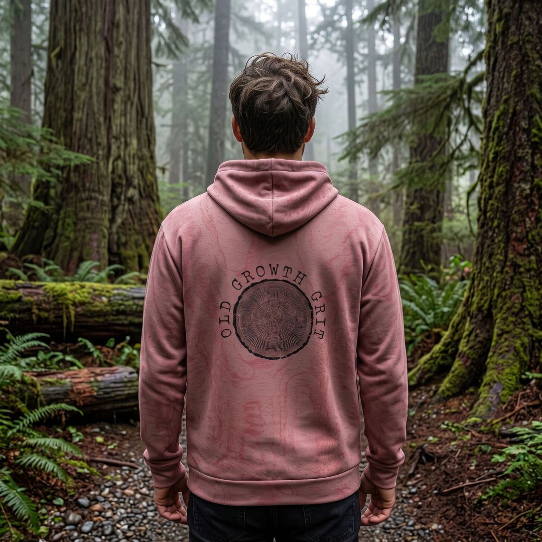 Casual man model wearing Old Growth Grit Hoodie outdoors in natural daylight with blurred foliage background.