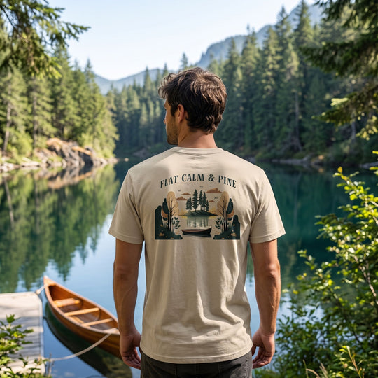 Model wearing Flat Calm and Pine Organic Tee outdoors with greenery, natural daylight, relaxed pose.