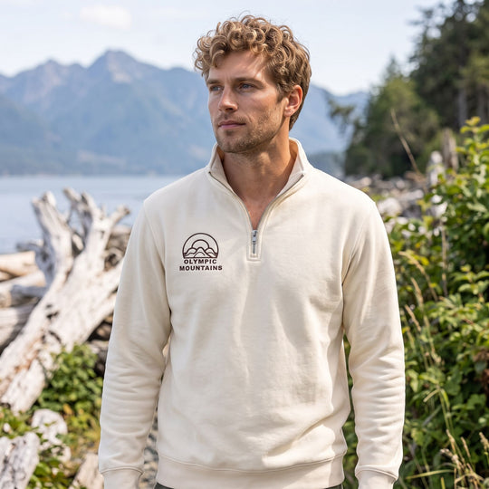 Adult male model wearing High-Divide Peak Quarter-Zip sweatshirt outdoors with greenery and natural sunlight.