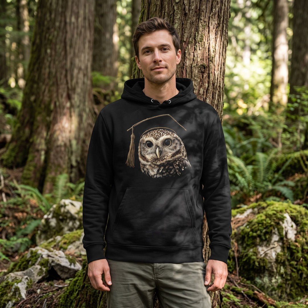 Casual model wearing The Night Dean heavyweight hoodie outdoors in a mossy forest with dappled sunlight, emphasizing the textured organic cotton fabric and relaxed fit.