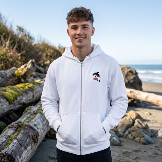 Young adult male model wearing an Orca Resist embroidered hoodie outdoors with greenery background.