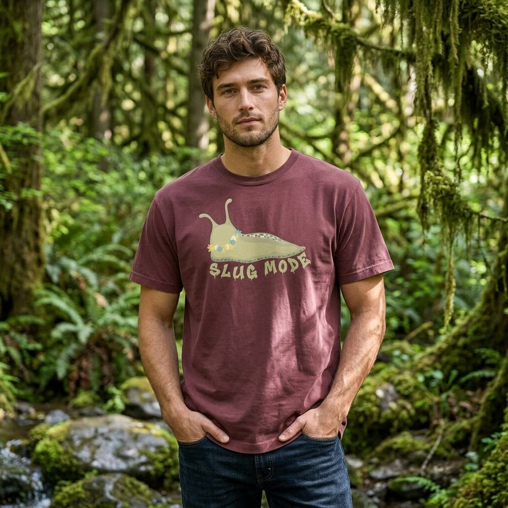 Model wearing the Slug Mode Heavyweight Tee outdoors with greenery, relaxed casual style, and natural lighting.