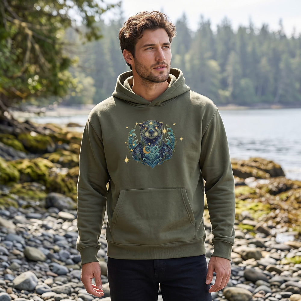 Model Alex wearing Aquarius River Otter hoodie outdoors among greenery, showcasing the soft fleece and playful design.
