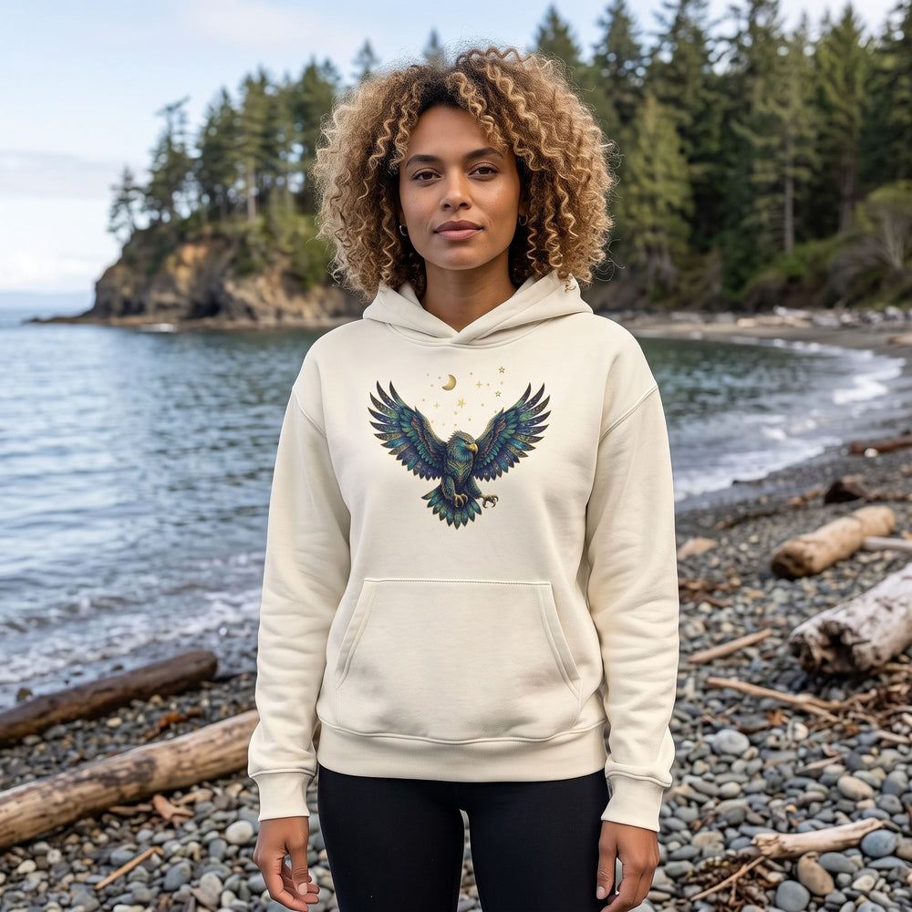 Adult model Zara wearing Scorpio Bald Eagle organic fleece hoodie outdoors with natural daylight, greenery, and blurred foliage in the background for a fresh, organic feel.