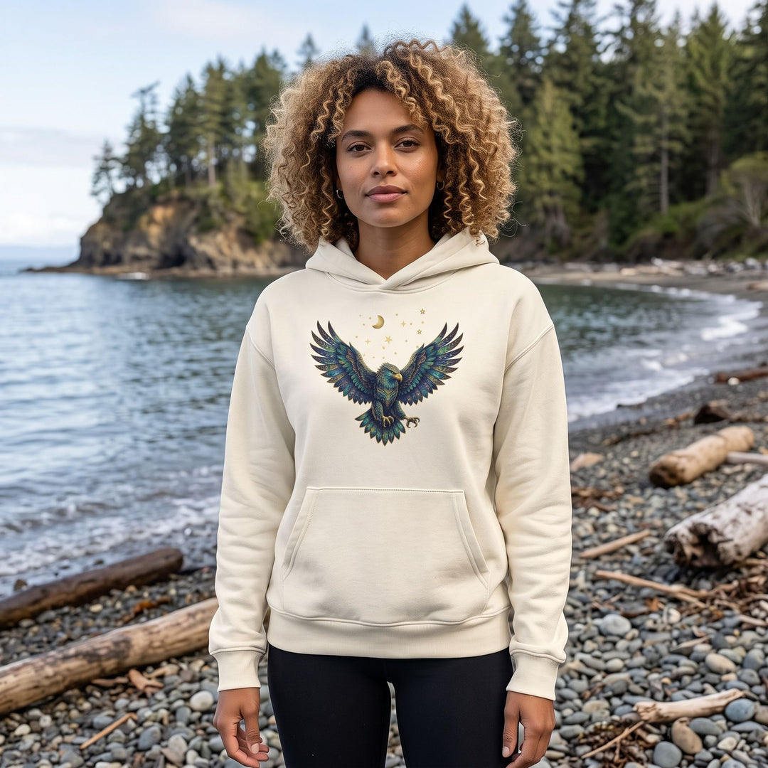 Adult model Zara wearing Scorpio Bald Eagle organic fleece hoodie outdoors with natural daylight, greenery, and blurred foliage in the background for a fresh, organic feel.