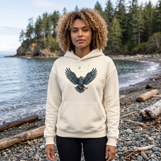 Adult model Zara wearing Scorpio Bald Eagle organic fleece hoodie outdoors with natural daylight, greenery, and blurred foliage in the background for a fresh, organic feel.