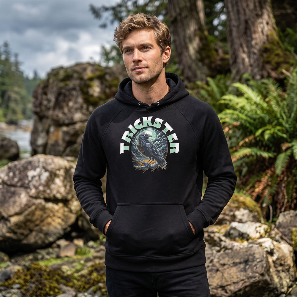 Model wearing Raven Raglan Sweatshirt outdoors among greenery, showcasing the stylized raven design in natural daylight.