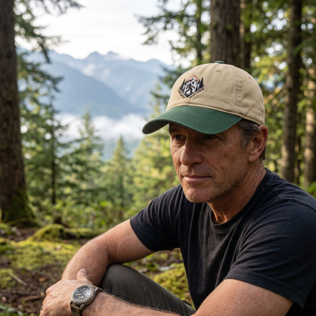 Casual outdoor scene featuring a worn Sasquatch Ridge Cap on a rugged explorer amid forest foliage and distant mountains.
