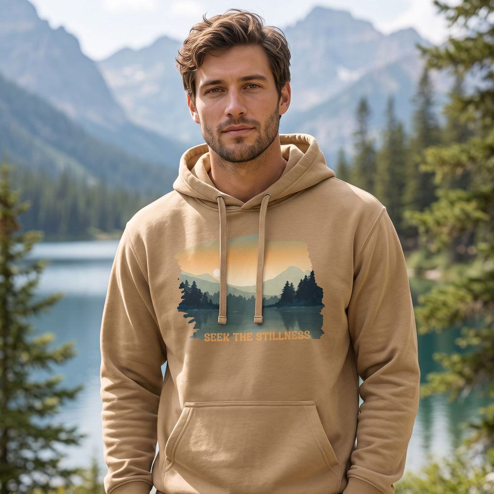 Model wearing Seek the Stillness hoodie in outdoor setting with greenery, natural daylight, relaxed style, and tranquil nature backdrop.