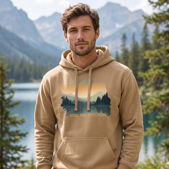 Model wearing Seek the Stillness hoodie in outdoor setting with greenery, natural daylight, relaxed style, and tranquil nature backdrop.