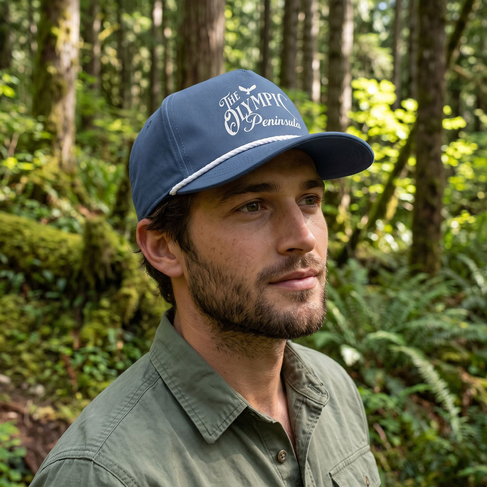 Casual man wearing The Olympic Peninsula Rope Cap outdoors with greenery in the background.
