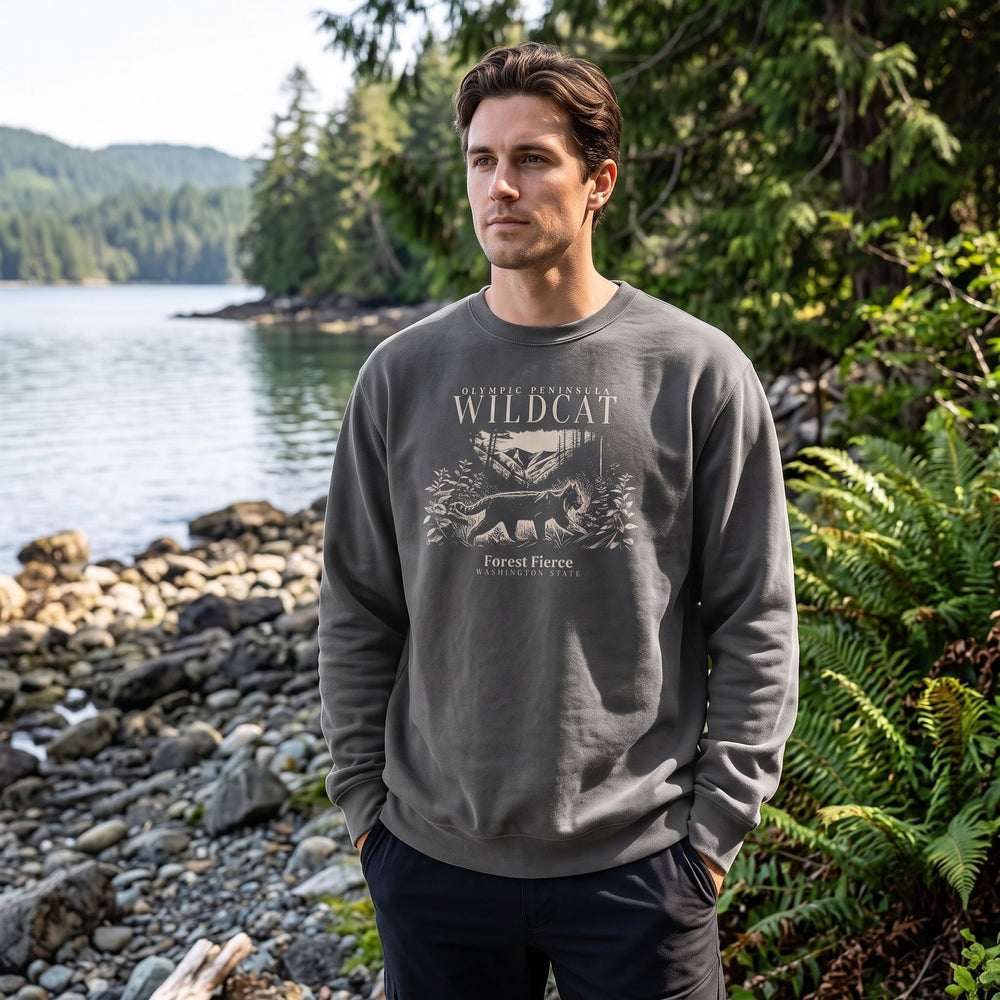 Model wearing the Forest Fierce Wildcat fleece crewneck by a calm water body with lush greenery, highlighting its vintage-washed texture and outdoors feel.