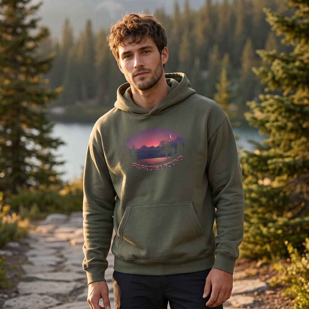Model wearing Paradise Found Organic Mid-Weight Hoodie in outdoor setting with greenery, natural daylight, relaxed pose, and blurred foliage background.