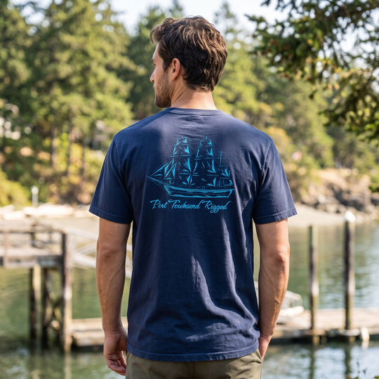 Casual male model wearing Port Townsend rigged heavyweight t-shirt outdoors with greenery background.