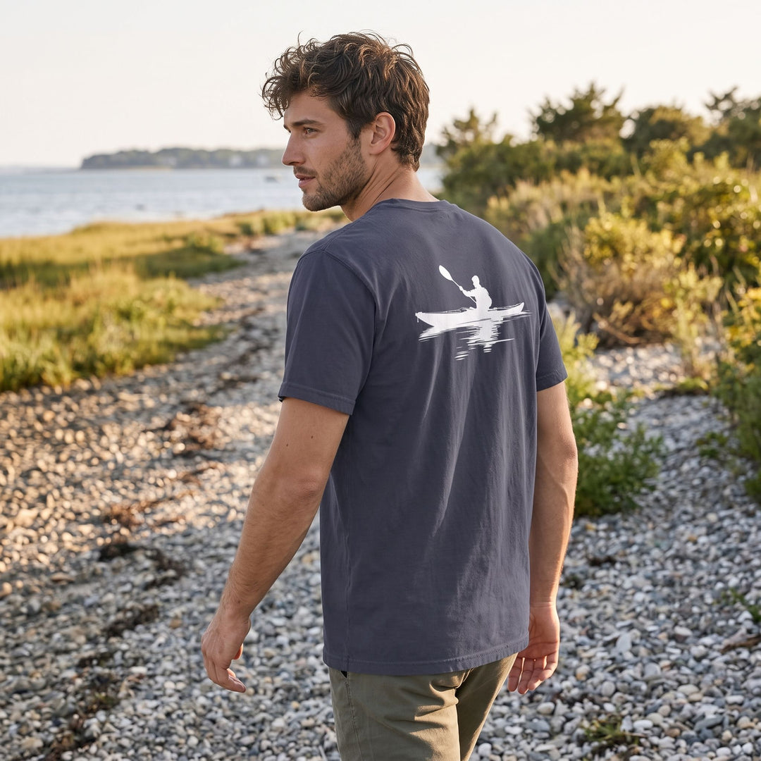 Model in outdoor setting wearing Strait Passage Pocket Tee with kayak emblem, emphasizing the versatile and durable fabric ideal for water and outdoor activities.