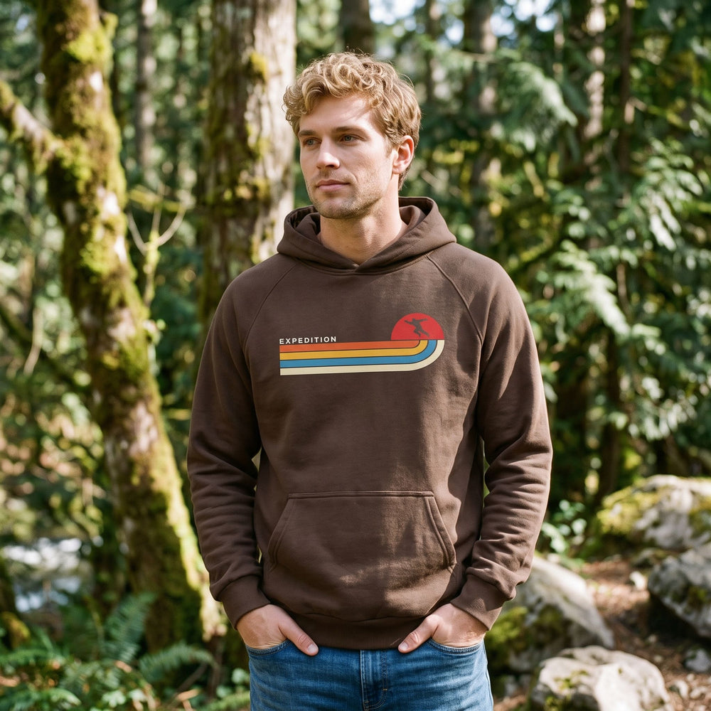 Man standing in forest wearing a super-heavyweight brown cotton-blend hoodie with a front kangaroo pocket and ribbed cuffs.