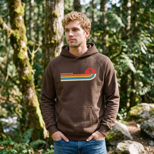 Man standing in forest wearing a super-heavyweight brown cotton-blend hoodie with a front kangaroo pocket and ribbed cuffs.