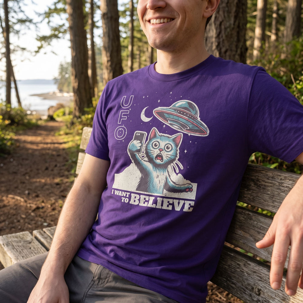 Casual model wearing the Close Encounter Selfie Tee in a peaceful wooded coastal area during early morning with soft sunlight.
