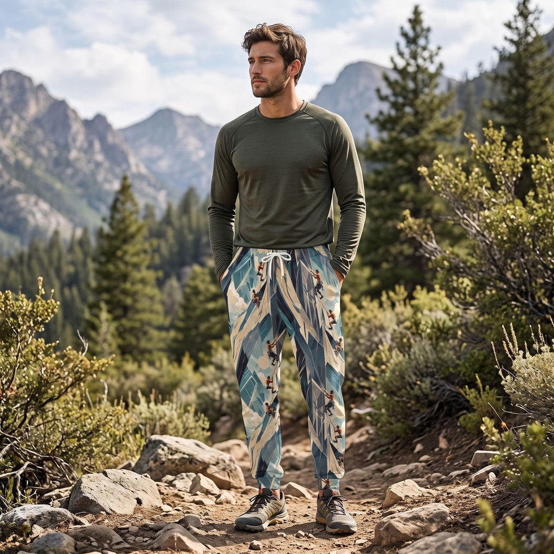 Casual man wearing rock deco joggers with climbing design, outdoors in natural daylight with greenery and sky elements.