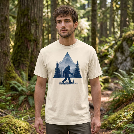 Model showcasing the High Country Wanderer Tee in an outdoor setting with blurred foliage, emphasizing its wilderness graphic and durable fabric.