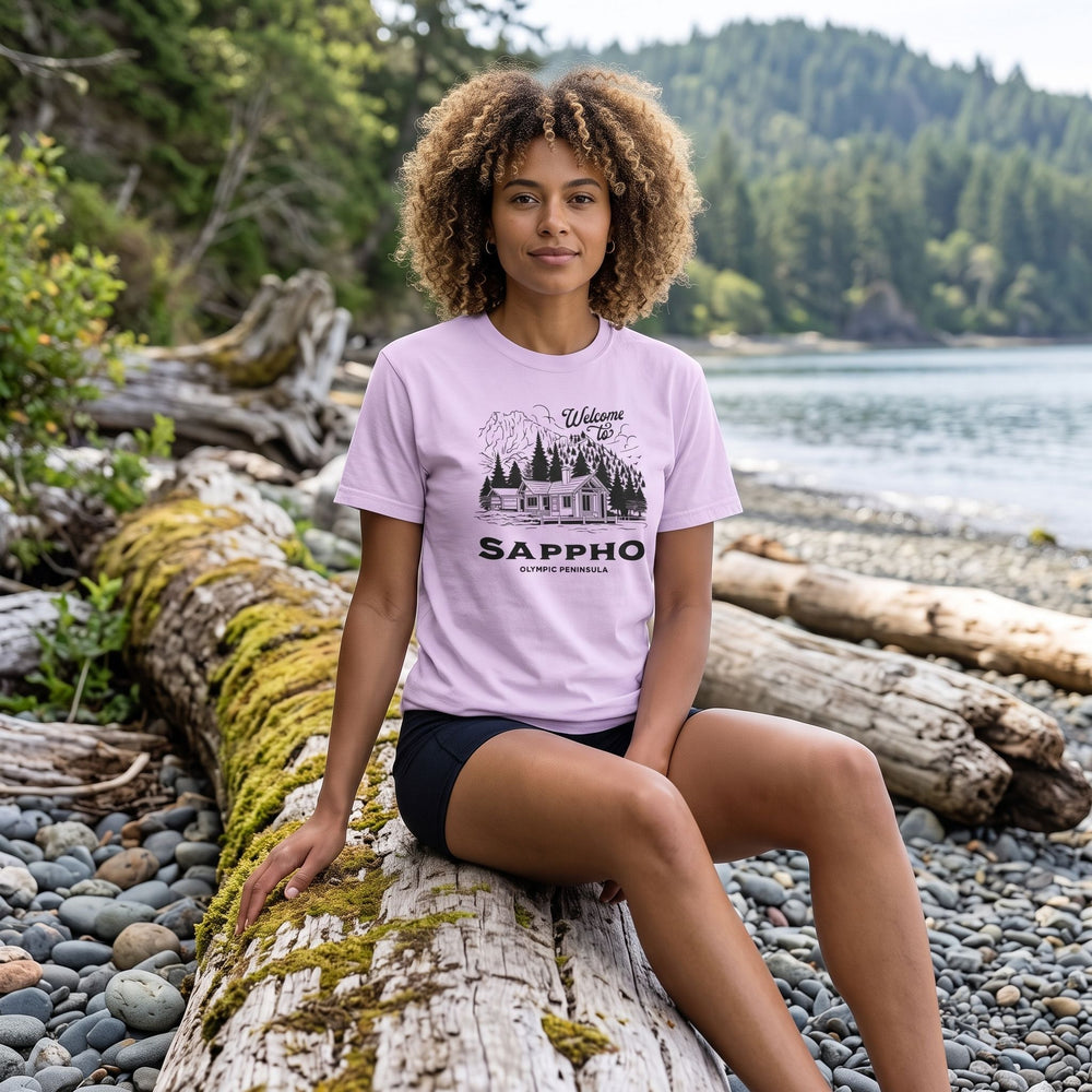 Adult model Zara wearing a retro-inspired mountain cabin tee in an outdoor setting with greenery, highlighting the vintage design and relaxed fit.